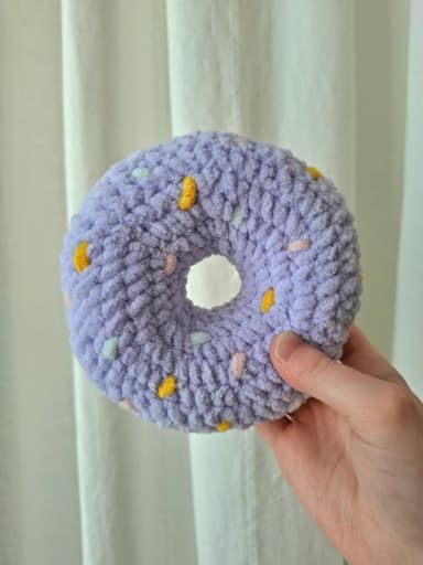 Itse tehty virkattu donitsi violeteilla yksityiskohdilla