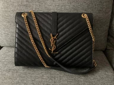 Bolso sobre de cuero negro Yves Saint Laurent con detalles dorados