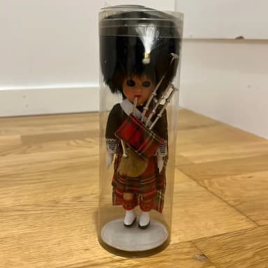 Scottish doll with bagpipe in plastic tube